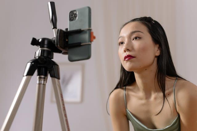 Una influencer grabando un primer plano de su rostro con un smartphone y un trípode.