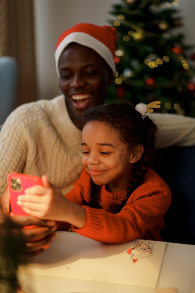 A dad and his young daughter smiling on a phone.