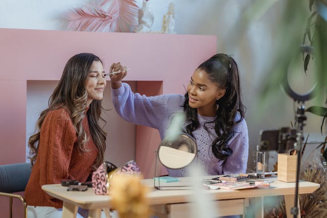 Two influencers recording a video of them using a beauty brand’s makeup products in a studio.