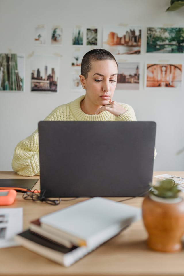 Een ernstig uitziende vrouw met een opgetrokken wenkbrauw die op een laptop werkt.