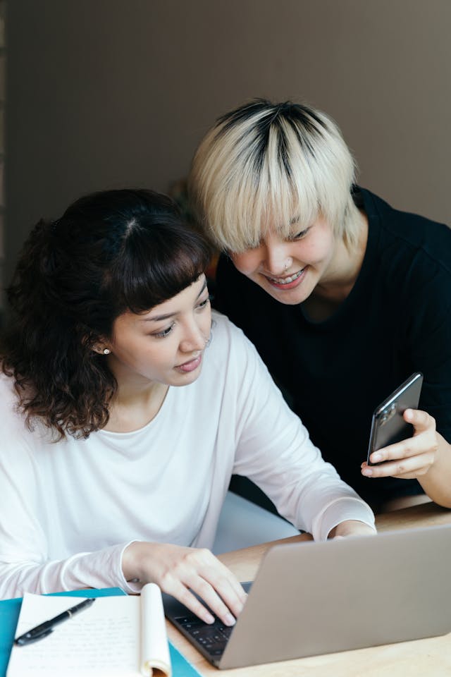 友人とソーシャルメディアの投稿を共有するために携帯電話を見せる女性。