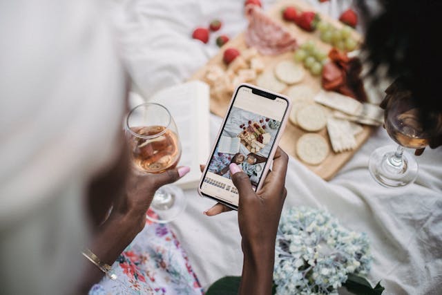 A woman taking an aesthetically pleasing flat-lay photo at an outdoor picnic.