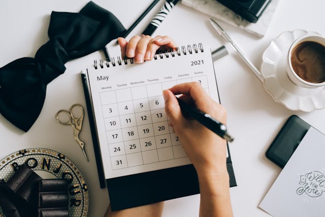 Alguien escribiendo notas en un calendario mensual.