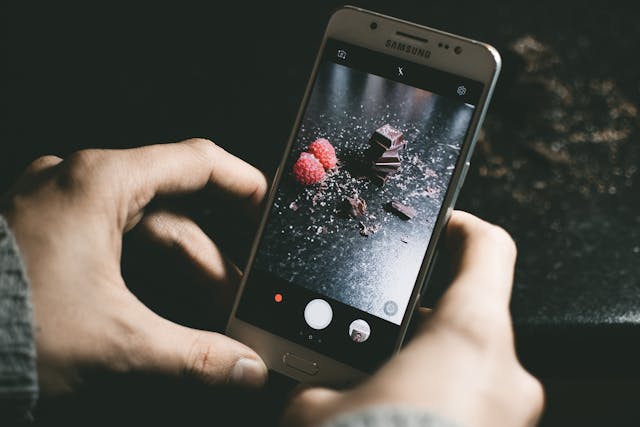 Quelqu'un qui prend une photo sombre et esthétique de chocolat et de framboises.