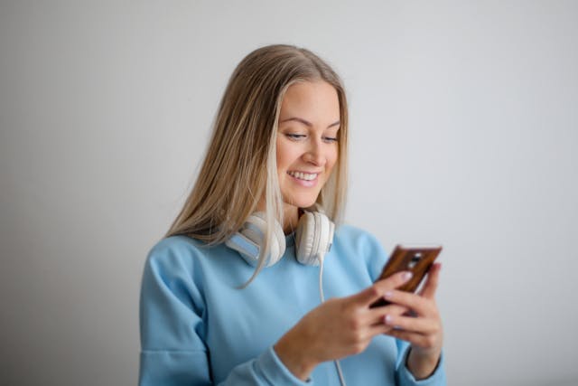 A woman smiling while typing something on her phone.