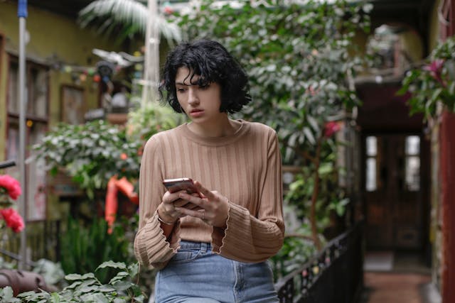 Una mujer piensa nerviosamente mientras sujeta su teléfono.