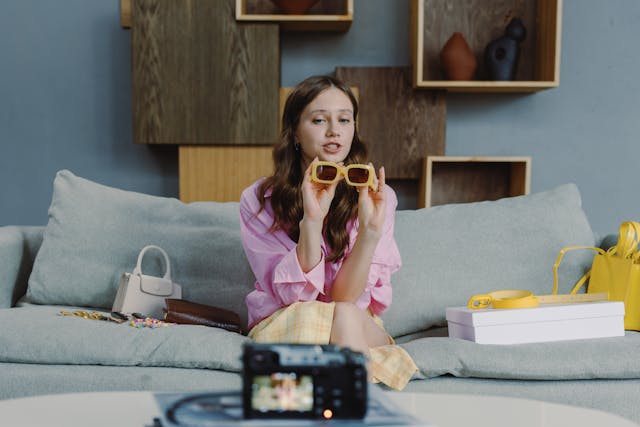 Una influencer donna che registra un video di se stessa parlando di un paio di occhiali da sole chic.