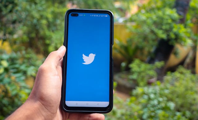 ツイッターのロゴが入ったiPhoneを持つ人。