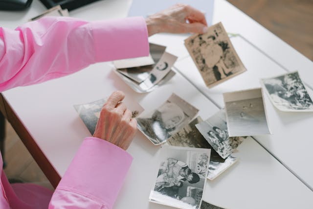 Een vrouw haalt herinneringen op door oude zwart-wit foto's te bekijken.