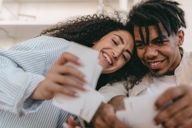 Um homem e uma mulher a sorrir e a acariciar-se enquanto olham para fotografias antigas.