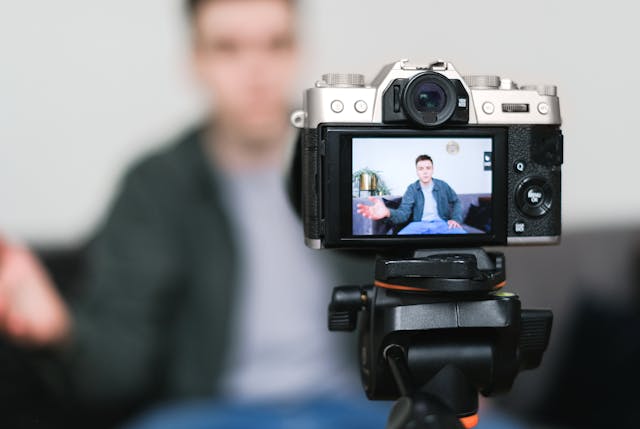 Un influenceur masculin filmant une vidéo avec sa caméra et son trépied.
