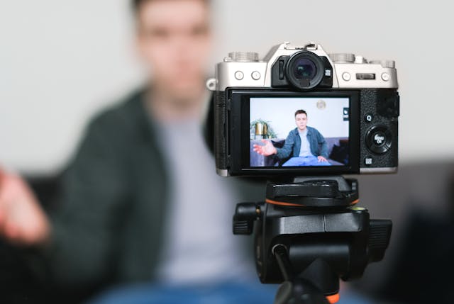 Um influenciador masculino a filmar um vídeo com a sua câmara e tripé.