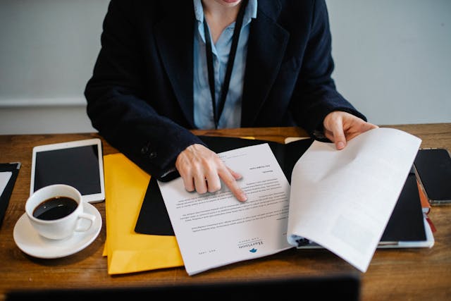 Een vrouw op een bureau leest en wijst naar de voorwaarden van een contract.