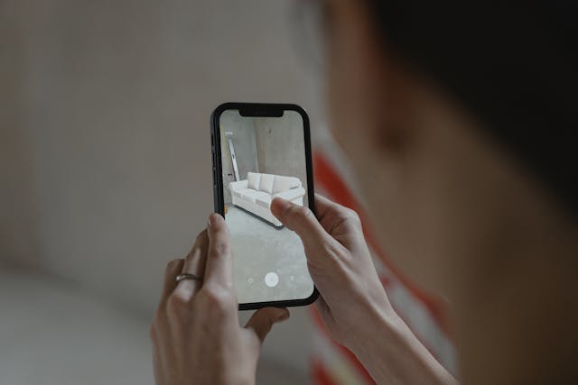 A woman using an immersive filter on her phone to see how a couch would look in an empty room.