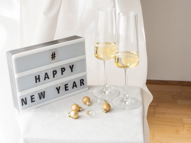 Taças de champanhe ao lado de um quadro com a hashtag #HappyNewYear.