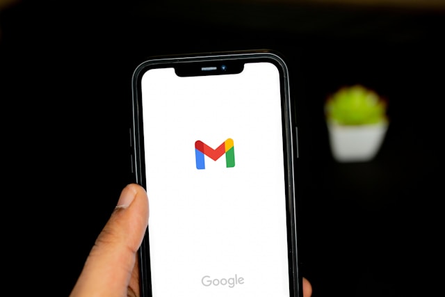 Jemand hält ein Telefon in der Hand, auf dem das Gmail-Symbol angezeigt wird.