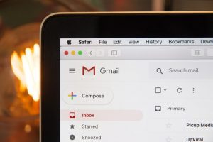 De hoek van een laptopscherm toont het Gmail-pictogram en enkele knoppen op de e-mailinterface.