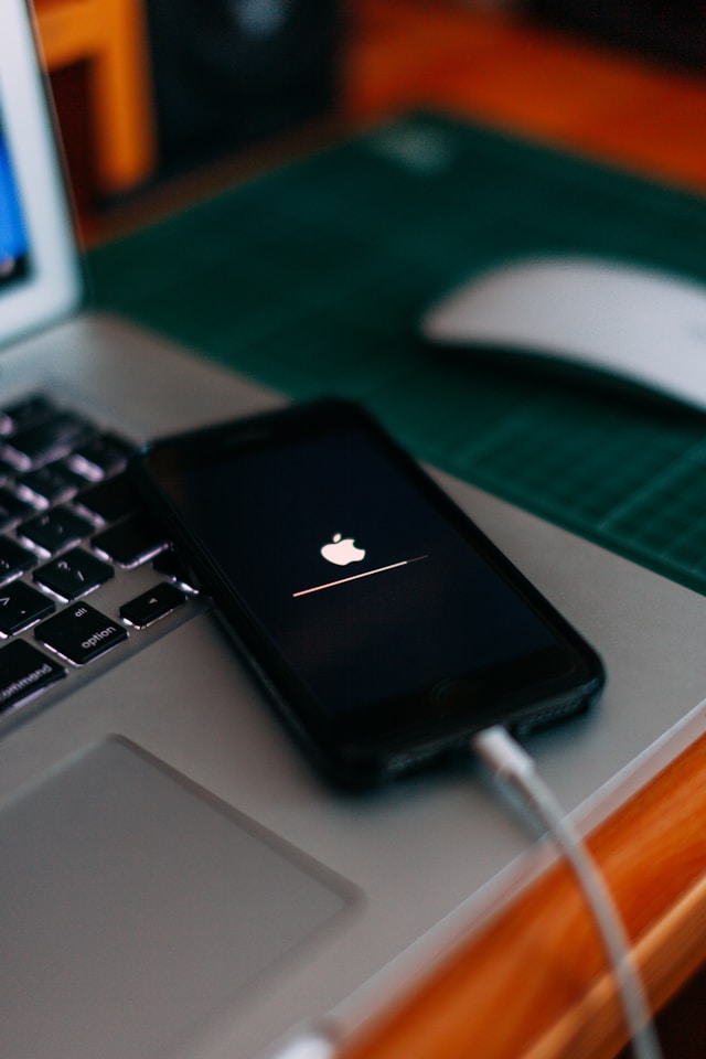 Een iPhone die wordt opgeladen bovenop een Macbook terwijl hij een systeemupdate uitvoert.
