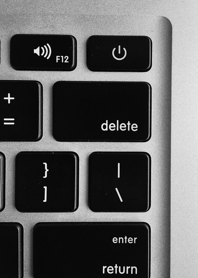 A close-up shot of the delete key on a black and silver Macbook keyboard.