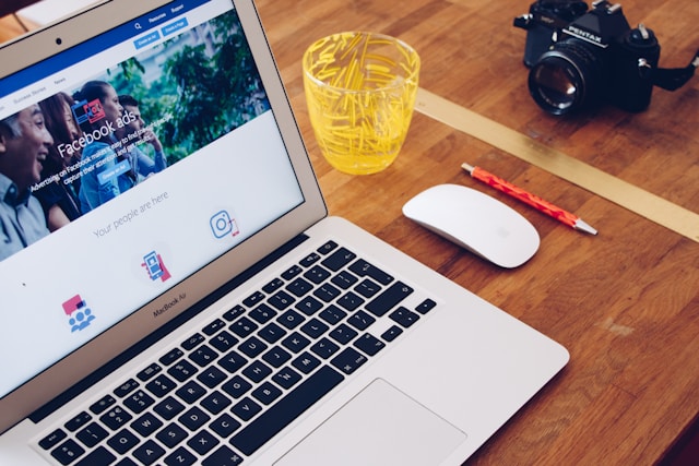 A laptop on a desk with a page about Facebook ads open on a browser.