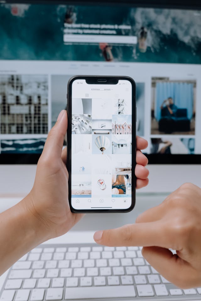 Une personne tenant un smartphone affichant un flux Instagram sur un thème blanc et minimaliste.
