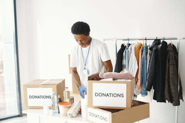 Um voluntário organiza uma mesa com caixas de donativos.