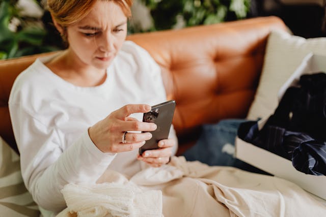 Eine Frau mit gerunzelten Brauen, die neugierig durch ihr Handy scrollt.