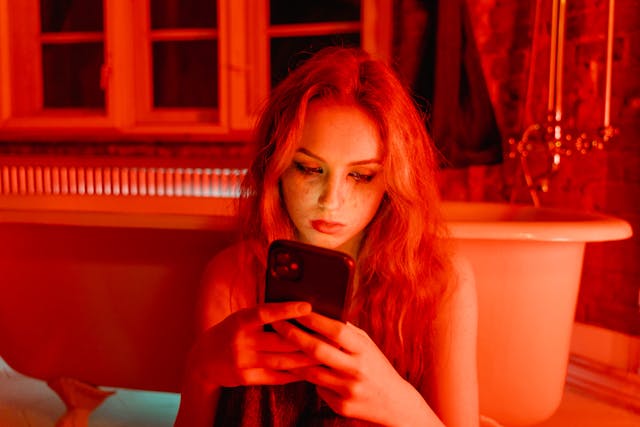 Une femme dont les yeux sont couverts de mascara et qui lit quelque chose sur son téléphone.