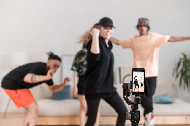 Un gruppo di amici filma un video di sfida di ballo sui social media con un telefono e un treppiede.