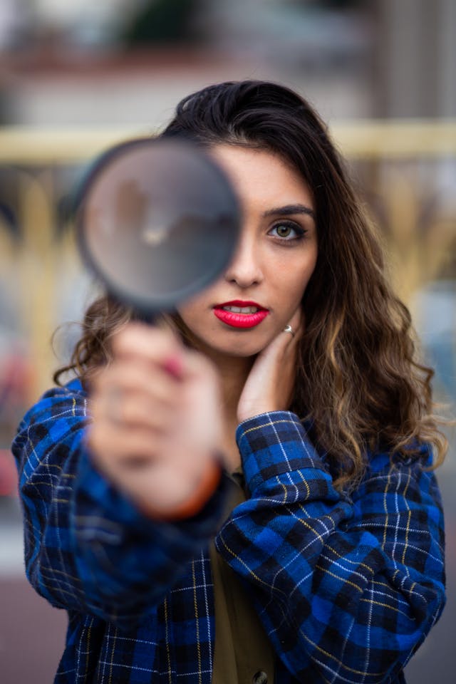 pexels-jorge-fakhouri-filho-861811-2530823 | Path Social A woman holding a magnifying glass in front of something before her.