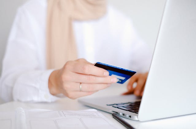 pexels-shvetsa-4482896 | Path Social Someone in a white button-down holding a credit card while purchasing something on their laptop.