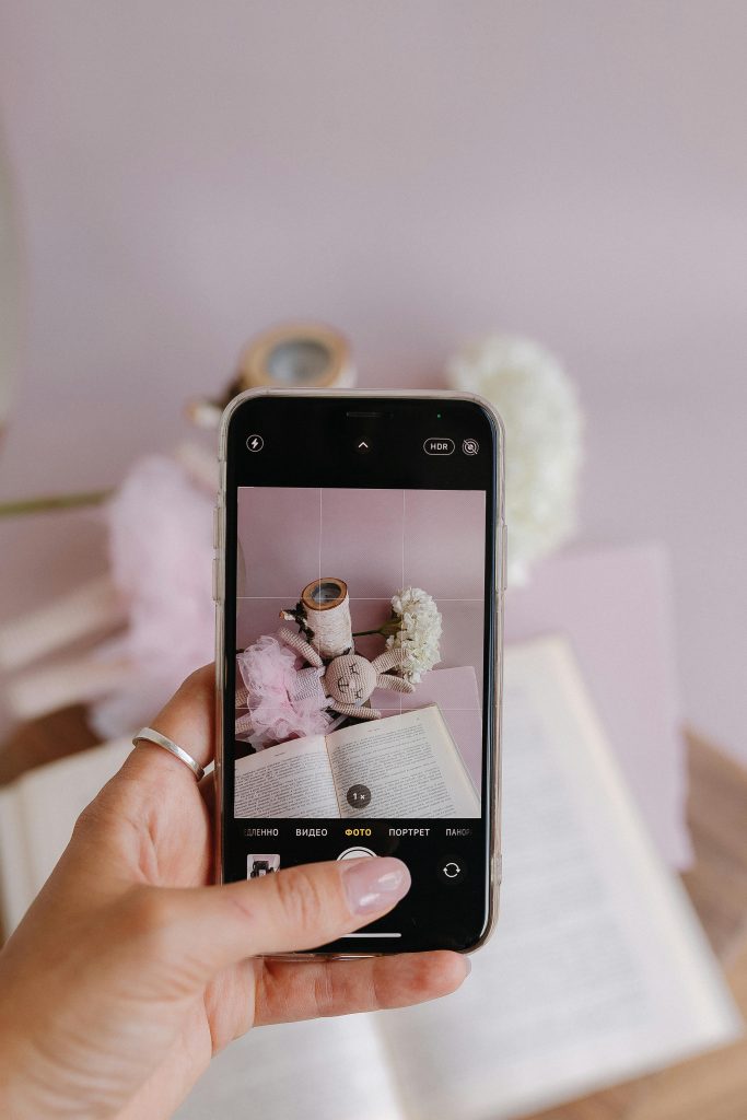 pexels-matvalina-27650004 | Path Social Jemand fotografiert ein aufgeschlagenes Buch und einen ausgestopften Hasen mit seinem Handy.