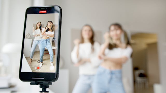 pexels-artempodrez-6003271 | Path Social Duas criadoras de conteúdos femininos a gravar um Reel de dança com uma câmara de telemóvel e um tripé.