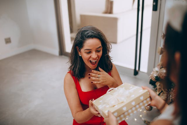 pexels-wildlittlethingsphoto-27086363 | Path Social Uma mulher de vestido vermelho com uma cara de surpresa depois de receber uma prenda de alguém.