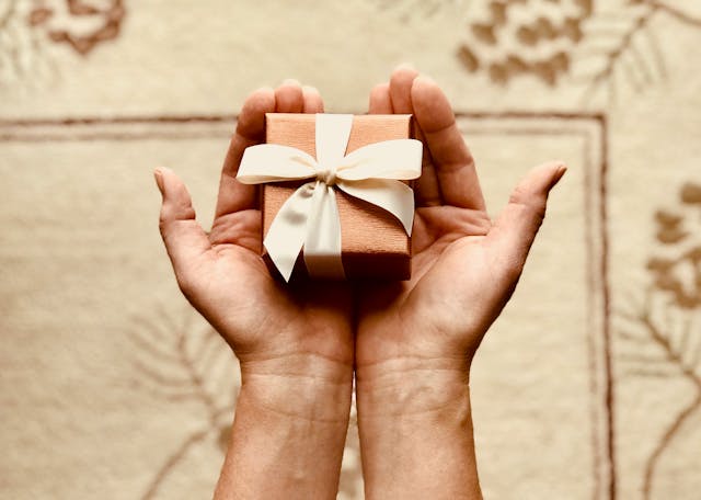 pexels-wordsurfer-842876 | Path Social Alguém com uma pequena caixa de presente castanha com um laço nas mãos.