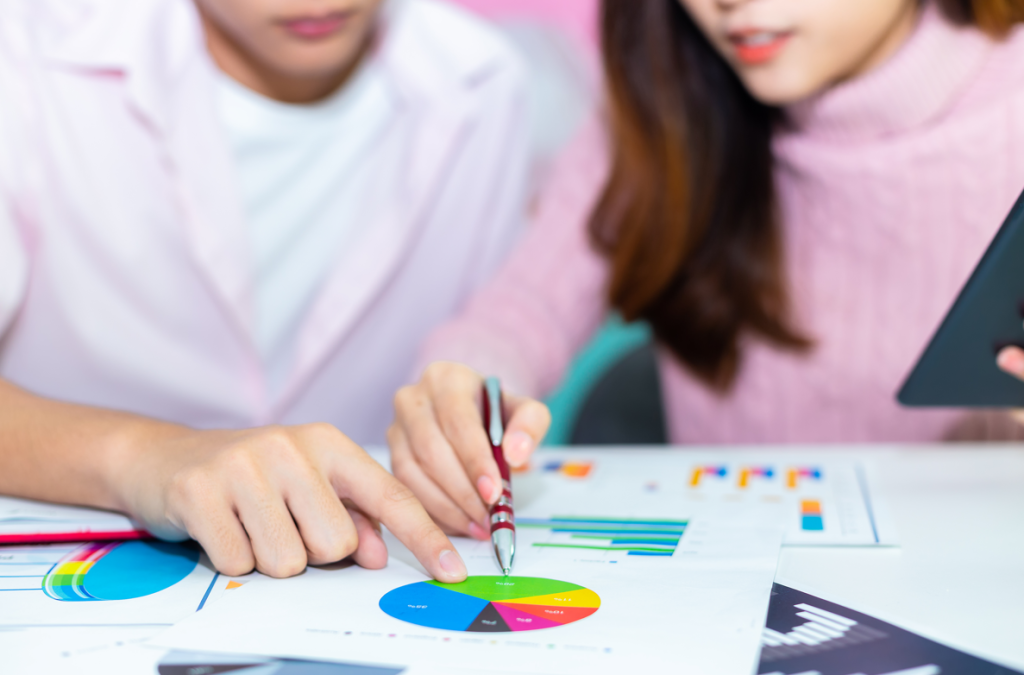 A man and a woman looking at graphs and discussing the data.