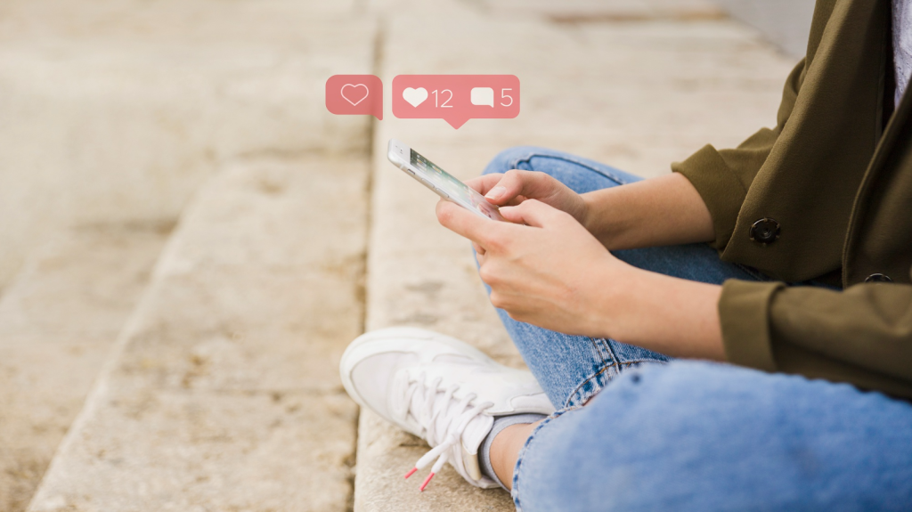 A woman is sitting on steps outside and holding a phone with likes and comments popping up.